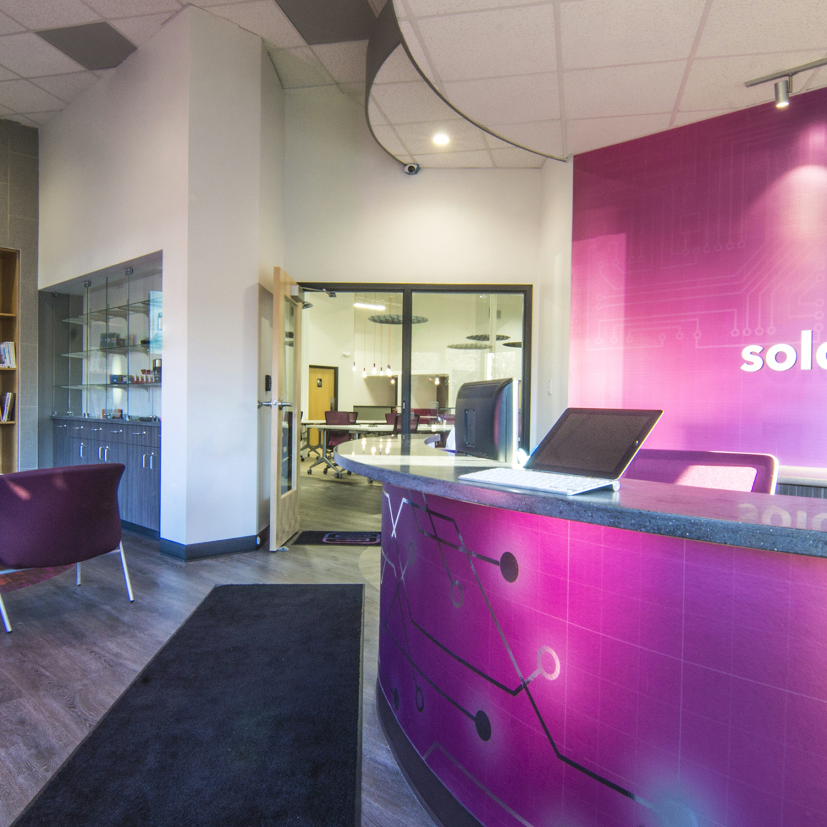 Vibrantly colored reception area of a tech office showing the reception desk, fireplace and seating area.