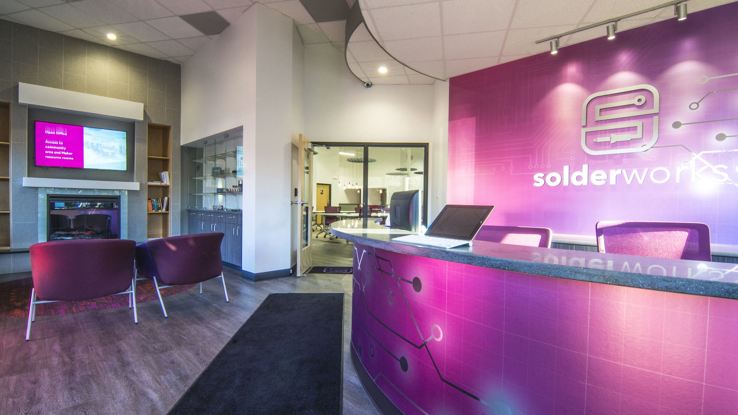 Vibrantly colored reception area of a tech office showing the reception desk, fireplace and seating area.